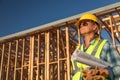 Female Construction Worker Holds Blueprints at Construciton Site