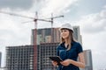 Female construction engineer. Architect with a tablet computer at a construction site. Young Woman looking, building