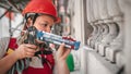 Female construction mason on the scaffolding, working with silicone gun