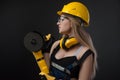 Female construction worker in a hard hat with angle grinder over black background Royalty Free Stock Photo