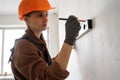 Female Construction worker in hardhat measuring concrete wall using spirit level during home renovation work Royalty Free Stock Photo