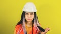 Female construction worker in overalls with hammer on yellow background in studio. Young woman in white hard hat slaps Royalty Free Stock Photo