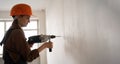 Female construction worker using hammer drill. Builder woman with pneumatic hammer drill perforator making hole in wall Royalty Free Stock Photo