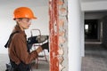 Female construction worker using hammer drill. Builder woman with pneumatic hammer drill perforator making hole in wall Royalty Free Stock Photo
