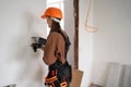 Female construction worker using hammer drill. Builder woman with pneumatic hammer drill perforator making hole in wall Royalty Free Stock Photo