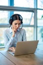 Female consultant of call center in headphones working on laptop at office. Royalty Free Stock Photo