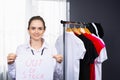 Female consultants of fashion store holding Out of Stock placard. Brunette consultant smiling at workplace