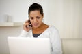 Female conversing on cellphone in front of laptop