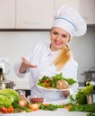 Female cook arranging herbs decoration on plate with salad