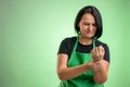 Female cook with green apron and black t-shirt has wrist pain