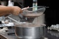 Female cook hands sifting cocoa for the preparation of a sweet cake