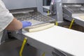 Female cook rolls dough on a dough sheeter for making dumplings, pelmeni