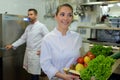 female cook in toque works with vegetables at commercial kitchen Royalty Free Stock Photo