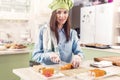 Female cook wearing Chef s hat and gloves making Japanese sushi rolls, smiling, looking at camera in the kitchen