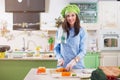 Female cook wearing Chef s hat and gloves making Japanese sushi rolls, smiling, looking at camera in the kitchen