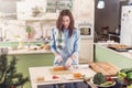 Female cook working in gloves making Japanese sushi rolls slicing them on bamboo mat standing in kitchen Royalty Free Stock Photo