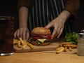 Female cooking fresh tasty homemade burger, serving with french fries and beverage Royalty Free Stock Photo