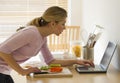 Female cooking and looking at laptop in kitchen Royalty Free Stock Photo