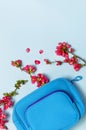 Female cosmetics bag, toiletry bag, travel bag, pink flowers on pastel blue background top view flat lay copy space. Minimalism