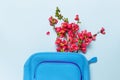 Female cosmetics bag, toiletry bag, travel bag, pink flowers on pastel blue background top view flat lay copy space. Minimalism