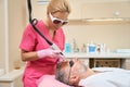 Female cosmetologist in glasses performs laser hair removal to man