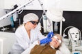 Cosmetologist making laser mole removal procedure for senior woman
