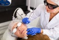 Cosmetologist making laser mole removal procedure for senior woman