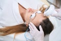 Female cosmetologist is performing forehead photorejuvenation procedure