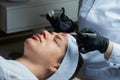 A female cosmetologist uses a brush to apply a face peeling to a girl Royalty Free Stock Photo