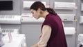 Female costumer checking the pricetag while choosing washing mashine in appliance store. Buying new household equipment