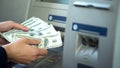 Female counting dollars withdrawn from ATM, 24h service, easy banking operation