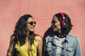 Female couple listening music and spending time together in a pink wall. A pair of young lesbian women couple, concept of same sex Royalty Free Stock Photo