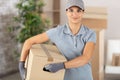 female courier with carboard box in residential room