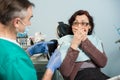 Female covering her mouth with both hands at the dentist appointment in the dental clinic Royalty Free Stock Photo