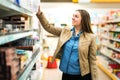 Female customer holding package or item in supermarket.