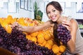 Female customer holding ripe bunch of grapes
