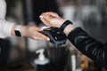 Female customer making wireless or contactless payment using smartwatch. Closeup of hands during payment. Store worker