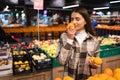 Female customer smelling orange in a supermarket. Woman chooses oranges. Girl at the fruit department of a grocery store. Royalty Free Stock Photo