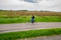 A female cyclist on bike path in Zaanse Schans. The Zaanse Schans is a typically Dutch small village in Amsterdam, Netherlands.