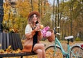 Female cyclist resting on bench near bike at autumn park. Royalty Free Stock Photo