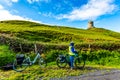 Female cyclist watching the Doonagore Castle tower in the coastal town of Doolin