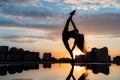 Female dancer showing her flexibility during sunset on cityscape background with reflection in the water. Concept of Royalty Free Stock Photo