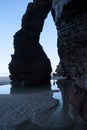 Female dancing in arch rock formations in the beach with sea in the background..