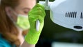 Female dentist adjusting light for regular dental examination of oral cavity