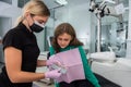 Female dentist checking and choosing teeth color with palette for girl Royalty Free Stock Photo