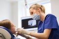 Female dentist checking patient girl teeth