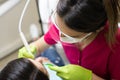 Female dentist cleaning teeth of patient