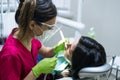 Female dentist cleaning teeth of patient at dental clinic.