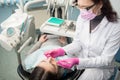 Female dentist with dental tools - mirror and probe checking up patient teeth at dental clinic office