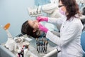 Female dentist with dental tools - mirror and probe treating patient teeth at dental clinic office. Medicine, dentistry